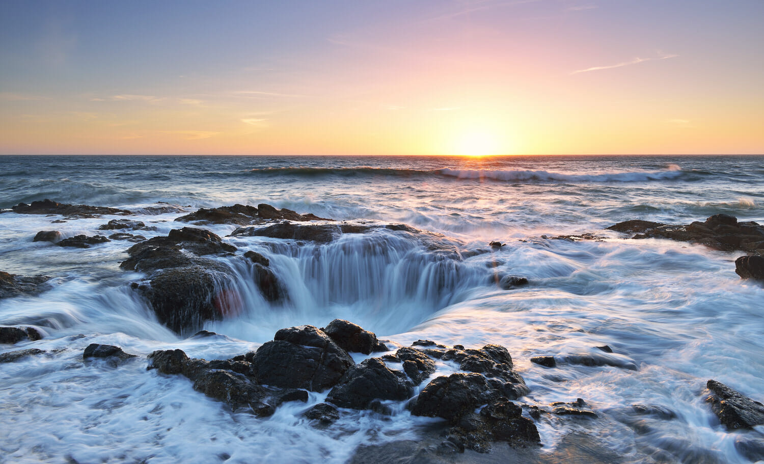 Thor's Well on the Oregon coast with ocean waves rushing into the rocks