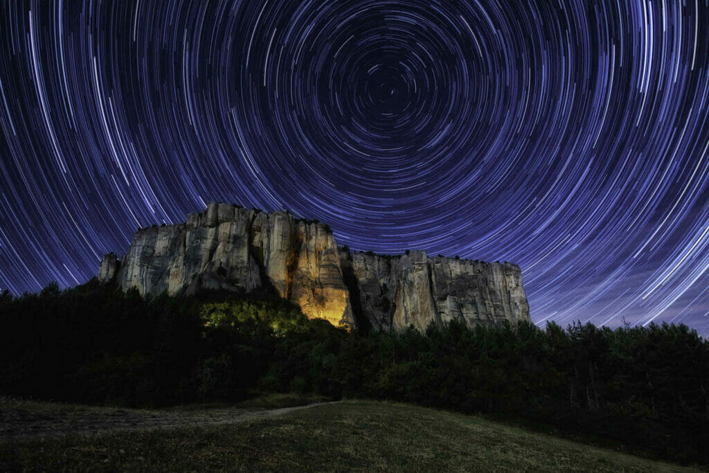 Circular star trail above the rocky plateau-shaped bismantova stone in italy