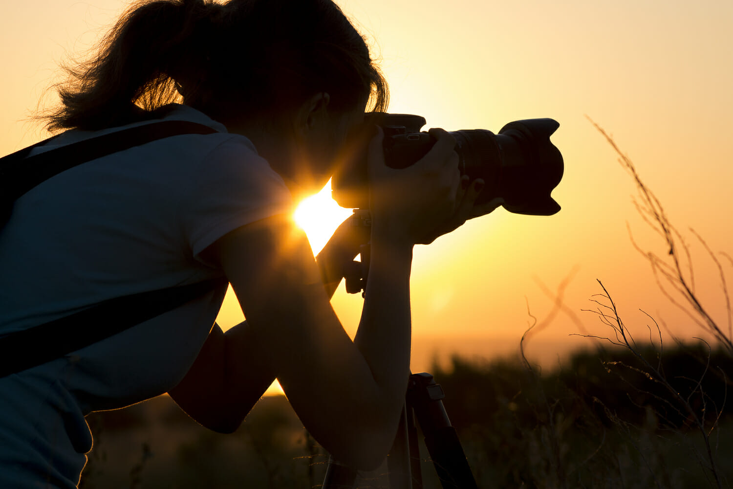 Woman photographing landscape at sunset