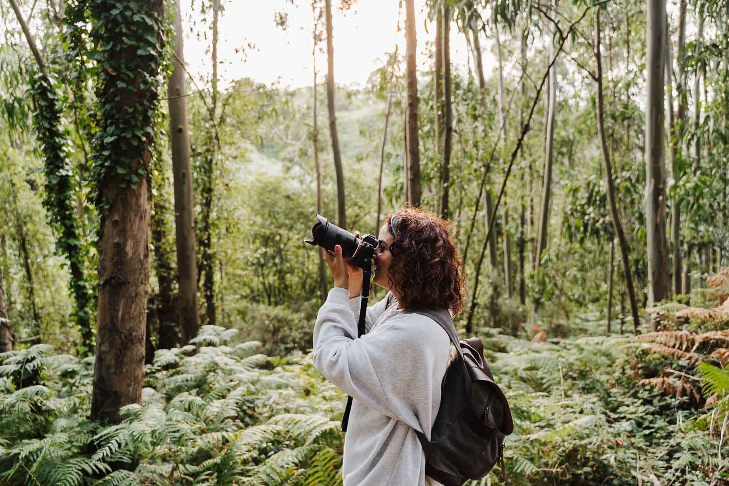 A person with binoculars observing nature in a lush forest.