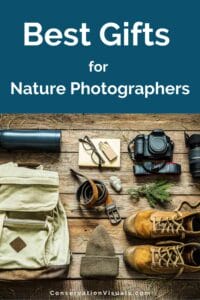 Essential items for nature photographers including camera equipment, notebook, backpack, and hiking boots displayed on a wooden surface.